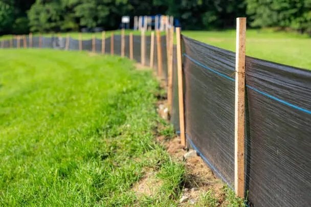 Row of staked silt fence running along a grassy site